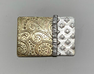 Etched brass with textured Precious Metal Clay and layered wot white metal strip